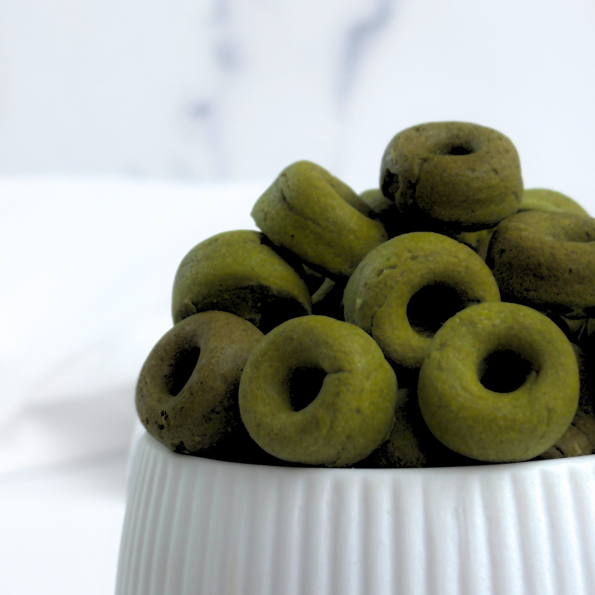 Superfood Spinach, Green Spirulina and Cottage Cheese Healthy Dog Treats in the shape of mini donuts. We call them Daisy Loops a playful color reference to Fruit Loops but for dogs.
